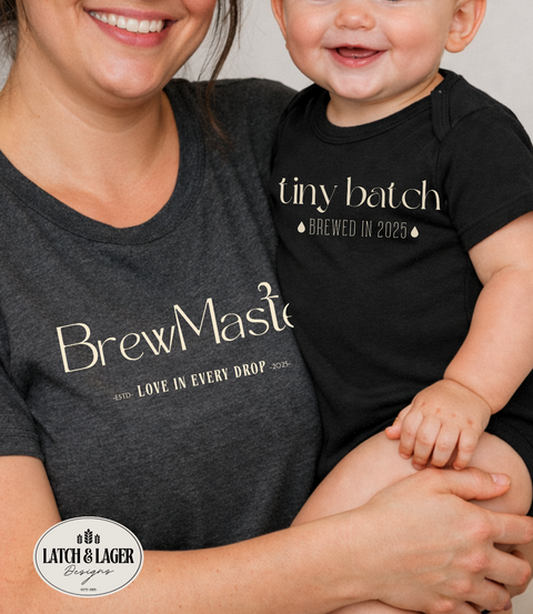 Woman holding a baby wearing a 'tiny batch brewed in 2023' shirt, both are smiling.