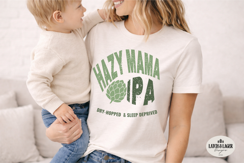 Woman wearing a 'Hazy Mama IPA' t-shirt holding a child, with a visible brand logo in the corner.