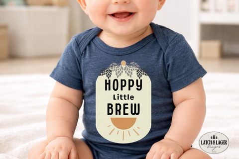 Baby wearing a blue onesie with 'Hoppy Little Brew' text, sitting on a light-colored surface.