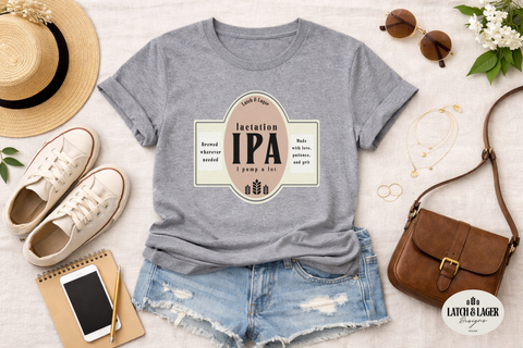 Gray t-shirt with 'Invention IPA' design, paired with denim shorts, sneakers, a hat, and handbag on a light surface.