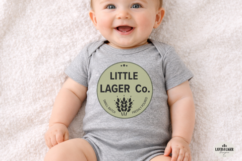 Baby wearing a gray onesie with 'Little Lager Co.' print on a light background