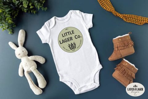 Baby onesie with 'Little Lager Co.' design, plush toy, and boots on a blue background