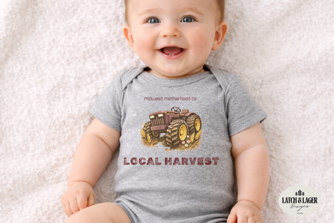 Baby wearing a grey bodysuit with Local Harvest and tractor and flowers.