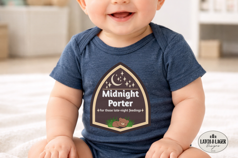 Baby wearing a blue onesie with 'Midnight Porter' design, sitting on a white surface.