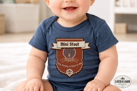 Baby wearing a blue onesie with a 'Mini Stout' design, sitting on a white surface.