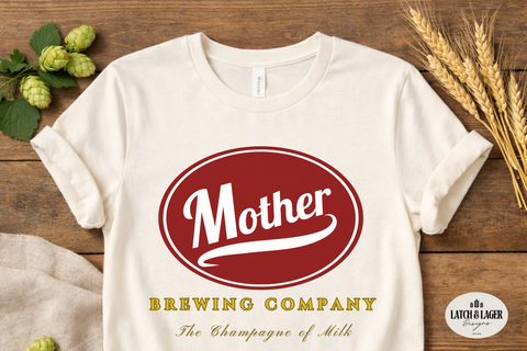 White t-shirt with 'Mother Brewing Company' logo on a wooden surface with hops and wheat.