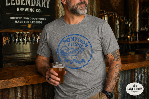 Man wearing a gray t-shirt with 'Pontoon Pilsner' design, holding a beer in a bar setting.