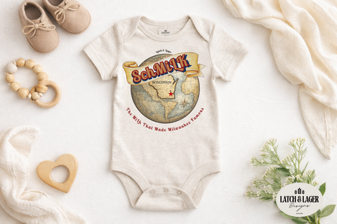 Baby onesie with a map design and text, surrounded by baby items on a light background