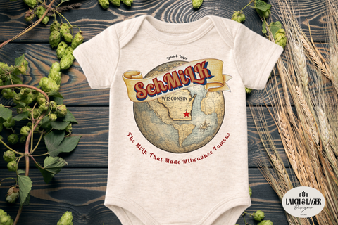 Baby onesie with 'SchMilk' design on a wooden surface with greenery