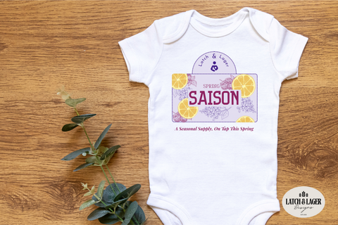 Baby onesie with 'Spring Saison' design on a wooden surface