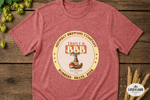 Red t-shirt with Midwest Brewing Company logo on a wooden surface with hops and wheat.