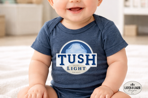 Baby wearing a blue onesie with 'TUSH Light' logo, sitting on a white surface.