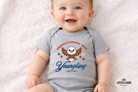 Baby wearing a gray onesie with an eagle graphic and text on a light background